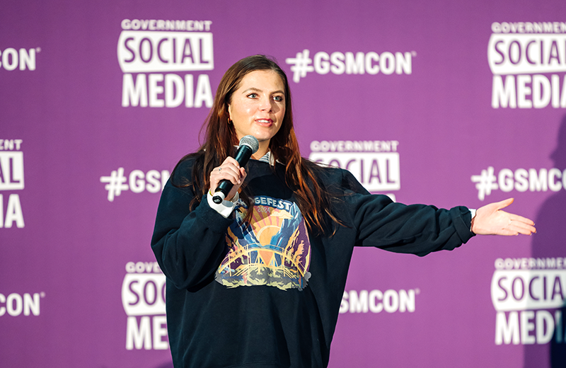 Photo of Aimee Colton speaking onstage at GSMCON2025 with a purple logo backdrop.